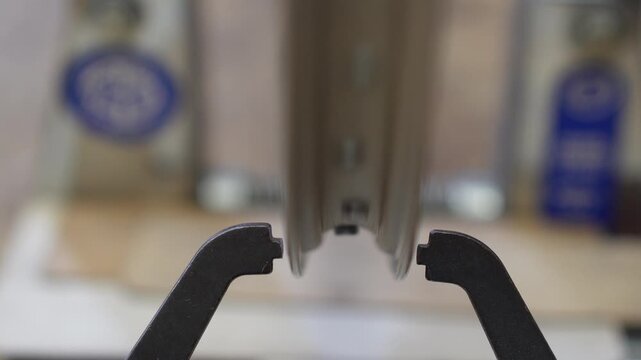 Close up of the gauge arms of a truing stand against the edge of a slowly turning bicycle rim. Checking lateral trueness of a wheel, shallow depth of field, real time 4K.