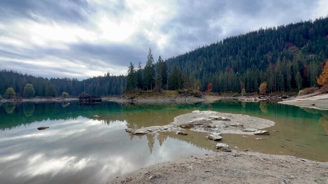 Autumn scenery at Lake Cauma in Flims, Switzerland, with its small island reflected in calm, mirror-like water beneath a cloudy sky, symbolizing tranquility, mindfulness and natural beauty.