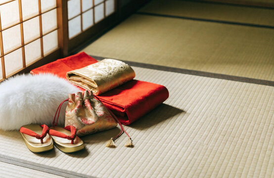 成人式の準備 畳の上に並べた赤い振袖と金の帯と白いファーショールと草履 和室