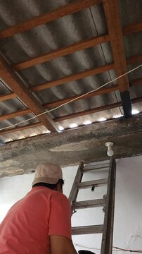 Young Man Climbing Ladder Carrying Black Paint Bucket