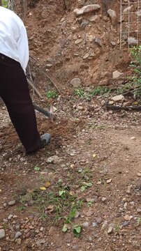 Young Person Digging Dirt with Pickaxe Tool