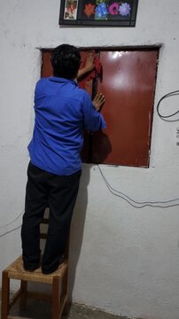 Young Person Stepping onto Wooden Chair to Clean Window