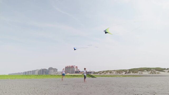 Boy and girl flying colorful kites on a sandy beach near dunes children on the seashore