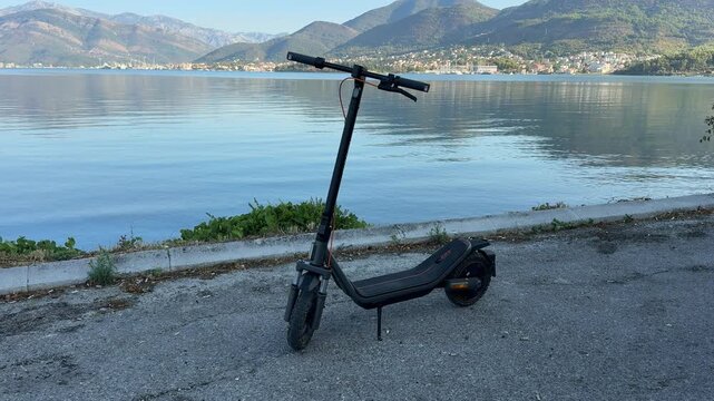 Black Electric Scooter Parked beside a Calm Coastal Bay