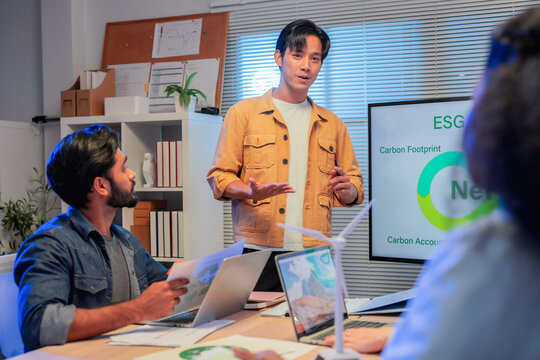Asian businessman presenting five key steps of ESG reporting process on screen to multiethnic colleagues during sustainability strategy meeting in office