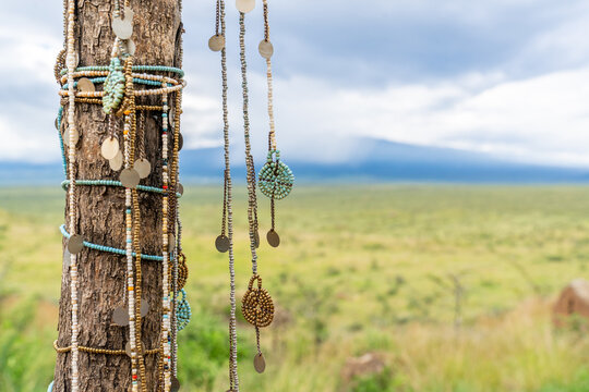 Maasai beaded jewelry hanging on a tree with Mount Meru and the Tanzanian savanna behind