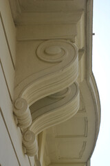 A low angle shot of ornate stone corbels with spiral scroll designs supporting a balcony on a historic building facade. © nahhan