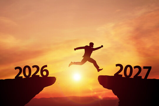 Silhouette of businessman jumping over cliff gap from year 2026 to 2027 at sunset. Concept of new year resolution, progress, challenge, and future growth.