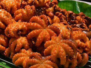 Golden fried octopus tentacle bites arranged on green banana leaf at food market © romaset