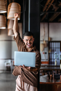 Excited investor celebrating stock market profit and financial success on laptop