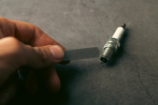 A person checks the spark plug gap.