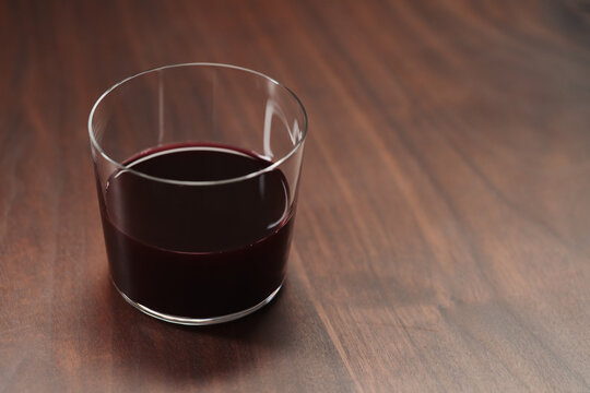 Red wine in tumbler glass on a walnut table with copy space
