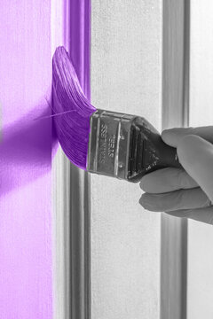 Painting a wooden panel door purple with a paint brush. Do it yourself home decorating project.