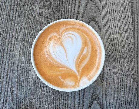 Cup of pumpkin spice latte on wooden table, flat lay