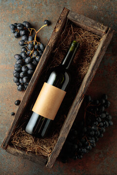Bottle of red wine in an antique wooden box and fresh grapes.
