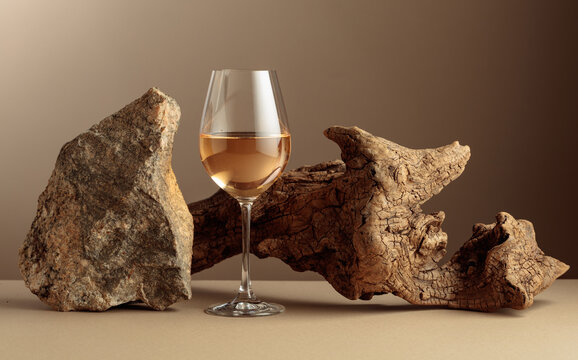 Glass of white wine with old driftwood and a piece of granite rock.
