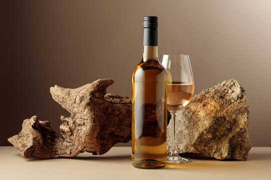 Glass and bottle of white wine with old driftwood and a piece of granite rock.