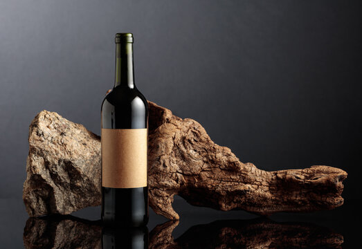Bottle of red wine with old driftwood and a piece of granite rock.