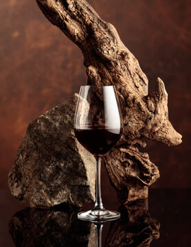 Glass of red wine with old driftwood and a piece of granite rock.