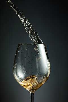 An image of white wine being splashed into a glass.