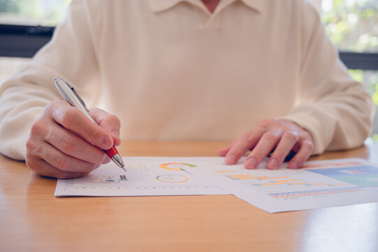 Businessman using pen and paper report while analyzing data at office, Financial analysis or business evaluation concept