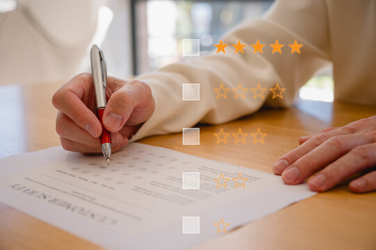 Customer service survey feedback and satisfaction concept, Businessman or client using pen give a feedback survey on paper form with stars and tick marks icons.