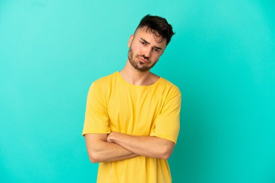 Young caucasian man isolated on blue background feeling upset