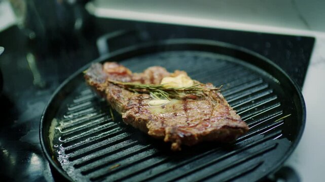 Seared beef steak with grill marks, melting butter, garlic and rosemary on a cast iron grill pan, French Riviera, France.