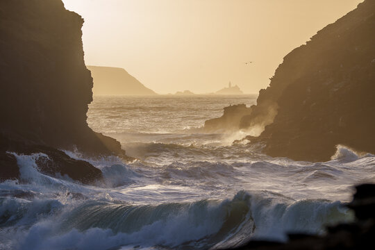 waves crashing on rocks with lighthouse 