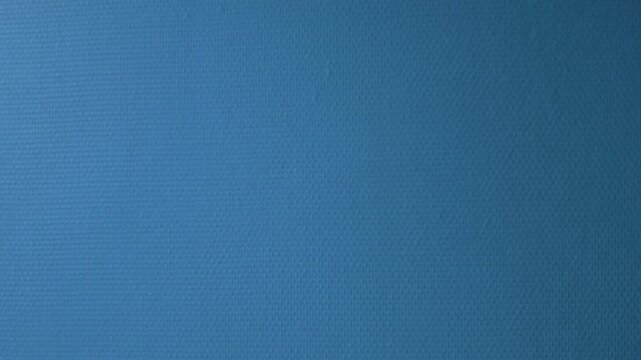 Deep blue painted wall surface with a canvas weave texture in changing light, minimal abstract background, French Riviera, France.