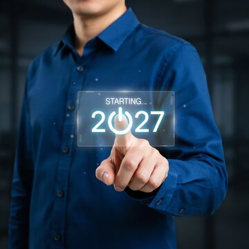 Professional businessman in blue shirt touching glowing futuristic virtual screen interface to start year twenty twenty seven