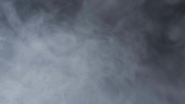 Thick white smoke clouds swirling against a dark background