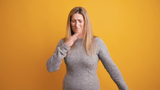 Unhappy woman with blonde hair feeling disgusted by a bad smell. She covers her nose with her hand, grimacing from the terrible stench