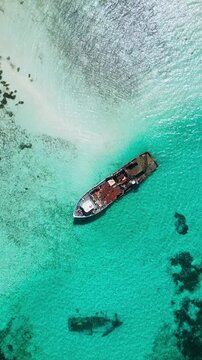 Stunning high angle drone view of exotic tropical ocean with turquoise lagoon and ancient shipwreck. Peaceful nature background scene for travel promo videos