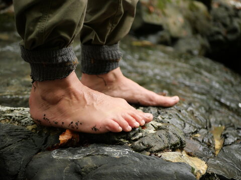 Bare feet standing on wet rocks during outdoor nature experience