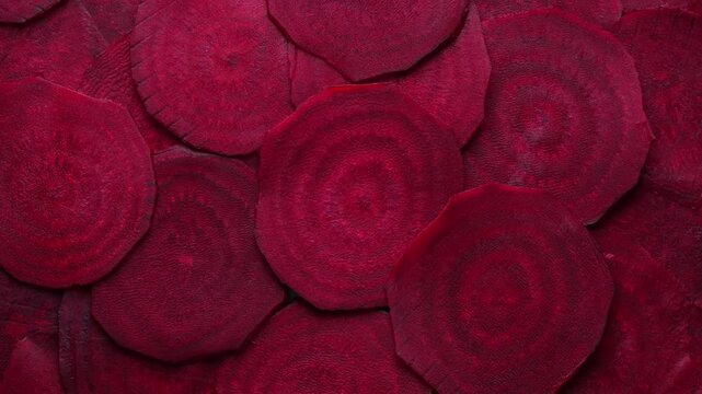 Top view of fresh cut beetroot slices backdrop, rotates.Full frame organic beet roots background for healthy food concept, cooking recipe, salad ingredients and agriculture marketing