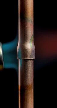 Torch Soldering Copper Tube Joints with Solder and Flux. Copper pipe connection receives torch heat during soldering with solder and flux. Heated fitting and adjoining tubing stand out.
