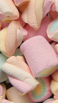 Colorful pastel marshmallows rotating close up. Vertical background video of sweet marshmallow texture. Spinning soft fluffy candy pile backdrop for childhood memories and sugar food concept.
