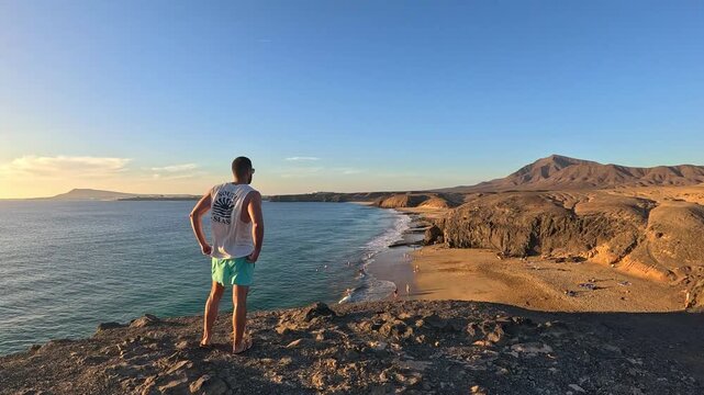 Young man approaching a cliff overlooking a beach in Lanzarote