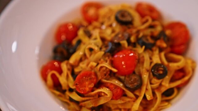 Fettuccine pasta with Arrabbiata sauce in a round plate, presented in a close up, showcases the rich textures of traditional Italian cuisine.