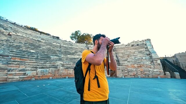 Patara Ancient City in Antalya features a young photographer capturing ancient ruins as the camera smoothly circles around him.