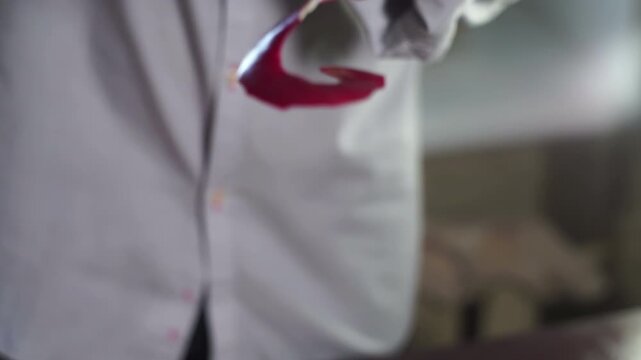 Long apple peel strip dangling hand closeup. Man holding curly red skin kitchen.