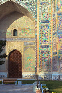 Bibi-Khanym Mosque facade detail in Samarkand showing intricate tilework and massive arched portal. Golden hour light illuminates turquoise and gold geometric patterns on the historic landmark.
