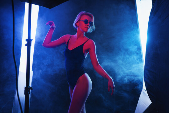 Portrait of fashion young girl in cool sunglasses in red and blue neon light in the studio