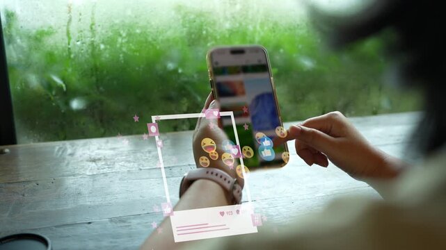 Sharing photos on social media, woman using smartphone with photo frames and emoji reactions by window
