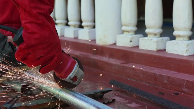 Locksmith Completing Metal Pipe Cut with Electric Angle Grinder Handheld Tool