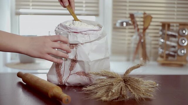 Woman scooping flour wooden spoon glass. Close up hands wheat ears rolling pin.
