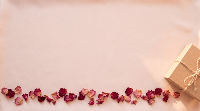 Craft gift box with string bow and dried flower petals creating a delicate border for celebration