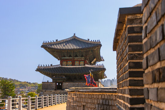 Historic fortress tower and stone wall ramparts under clear blue sky   