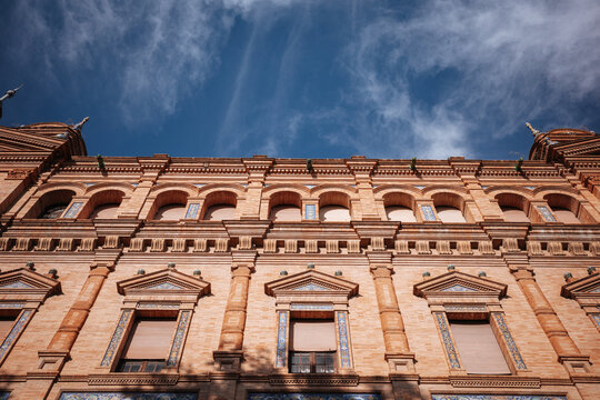 Historic brick facade and arches beneath blue sky in Seville